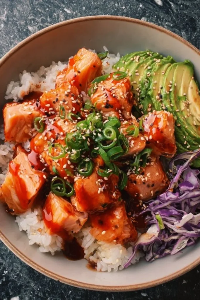 Delicious spicy salmon bowl with fresh vegetables and rice garnished with sesame seeds.