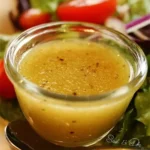 A bowl of homemade Olive Garden salad dressing, fresh ingredients and herbs.