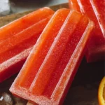 Homemade Orange Strawberry Popsicles on a wooden table