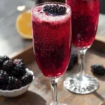 A refreshing glass of Blackberry Mimosas garnished with fresh blackberries