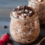 Bowl of Triple Chocolate Overnight Oats topped with chocolate chips and strawberries.